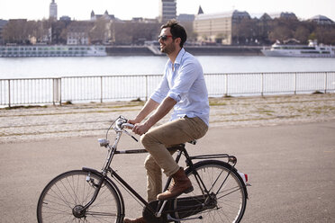 Man riding bicycle on riverbank - FMKF001191