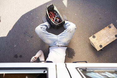 Man lying on ground repairing car - FMKF001202