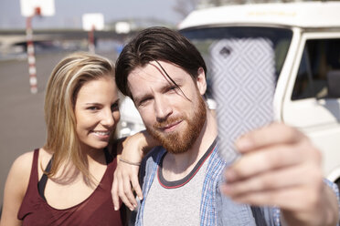 Man taking selfie with girlfiend in front of car - FMKF001213