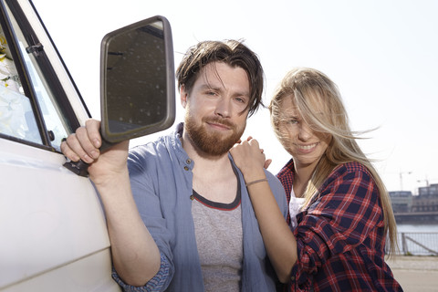 Porträt eines lächelnden Paares am Auto, lizenzfreies Stockfoto