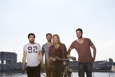 Four smiling friends with bicycle - FMKF001242