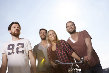 Vier lächelnde Freunde mit Fahrrad - FMKF001243
