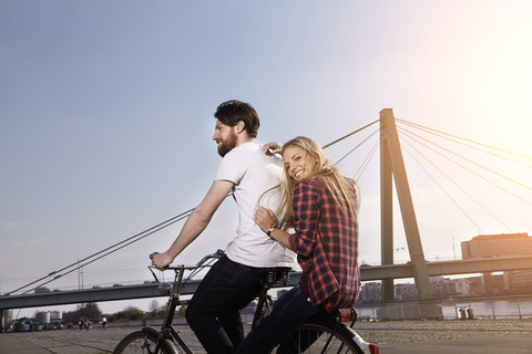 Glückliches Paar beim Fahrradfahren am Flussufer, lizenzfreies Stockfoto