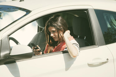 Spain, Barcelona, Young woman with cell phone in car - EBSF000226