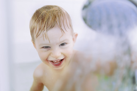 Porträt eines kleinen Jungen, der mit einem Duschkopf spielt, lizenzfreies Stockfoto