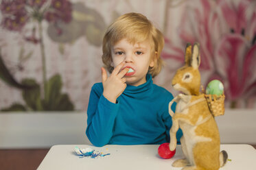 Blonder Junge mit Osterhase isst Ei - MJF001037