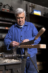 Germany, Bavaria, Josefsthal, blacksmith working at bench vice in historic blacksmith's shop - TCF003965