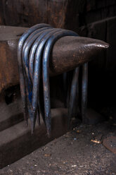 Germany, Bavaria, Josefsthal, blue metal hooks hanging on anvil beak at historic blacksmith's shop - TCF003937