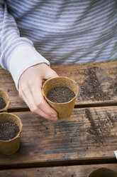 Boy holding nursery pot with bell pepper seeds, partial view - LVF001132