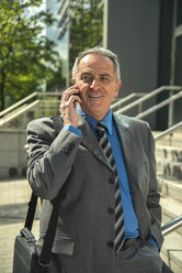 Senior businessman on cell phone outdoors - UUF000334
