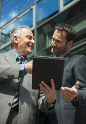 Zwei Geschäftsleute mit digitalem Tablet vor einem Bürogebäude - UUF000348
