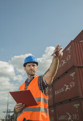 Man with clipboard wearing reflective vest at container port - UUF000412