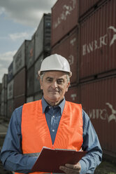 Mann mit Klemmbrett und Warnweste im Containerhafen - UUF000419