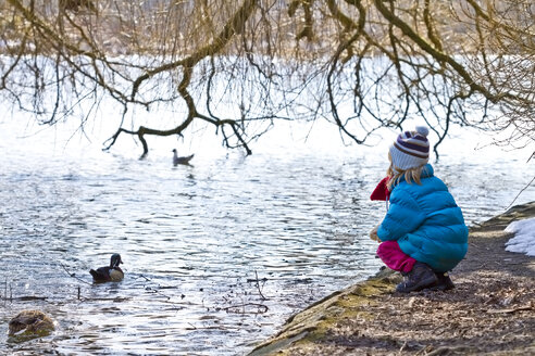 Kleines Mädchen hockt am Ufer eines Teiches - JFEF000328