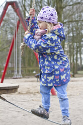 Kleines Mädchen balanciert auf Kette auf Spielplatz - JFEF000406