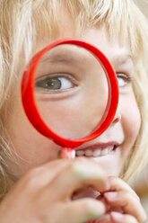 Portrait of little girl looking through magnifying glass - JFEF000335