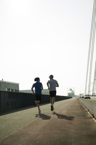 Junger Mann und Teenager laufen auf einer Brücke, lizenzfreies Stockfoto