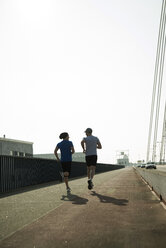 Young man and teenager running on bridge - UUF000399