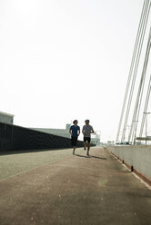 Young man and teenager running on bridge - UUF000400