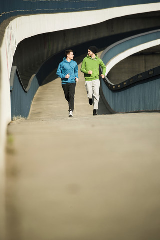 Junger Mann und Teenager laufen auf einer Brücke, lizenzfreies Stockfoto