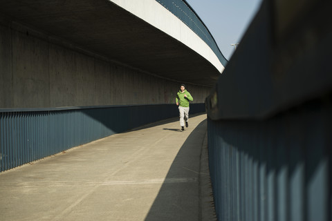 Junger Mann läuft auf Brücke, lizenzfreies Stockfoto