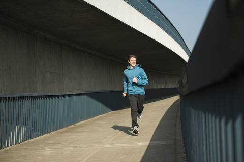 Young man running on bridge stock photo