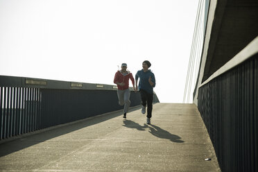 Young man and teenager running on bridge - UUF000429