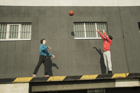 Junger Mann und Teenager spielen Basketball, lizenzfreies Stockfoto