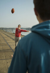 Junger Mann und Teenager spielen Fußball am Flussufer - UUF000439