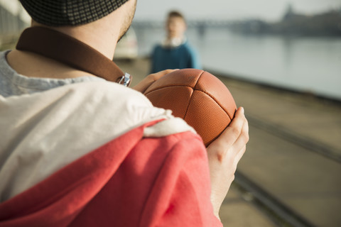 Junger Mann und Teenager spielen Fußball am Flussufer, lizenzfreies Stockfoto