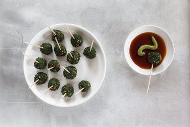 Plate of skewered spinach sesame balls and dipping bowl of sauce, elevated view - EVGF000554