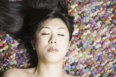 Porträt einer asiatischen Frau mit geschlossenen Augen vor einem bunten Boden - FLF000500