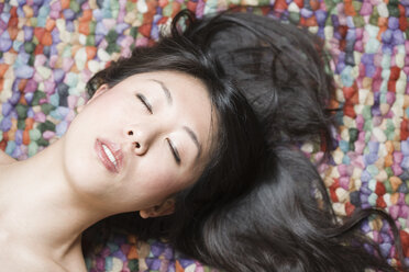 Porträt einer asiatischen Frau mit geschlossenen Augen vor einem bunten Boden - FLF000502