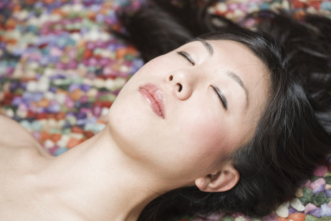 Porträt einer schlafenden asiatischen Frau vor einem bunten Boden, lizenzfreies Stockfoto