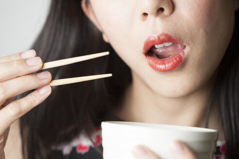 Asiatische Frau isst mit Essstäbchen - FLF000508