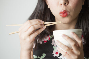 Asiatische Frau isst mit Essstäbchen - FLF000509