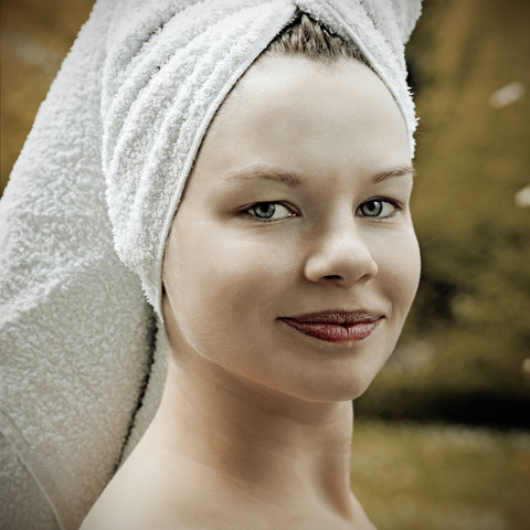 Porträt einer lächelnden Frau mit Handtuch auf dem Kopf, lizenzfreies Stockfoto