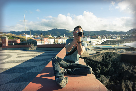 Portugal, Azoren, Sao Miguel, Mann an der Wand beim Fotografieren, lizenzfreies Stockfoto