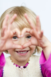 Porträt eines kleinen Mädchens, das mit den Fingern ein Herz formt - JFEF000389