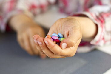 Hand of little girl holding chocolate drops - JFEF000392