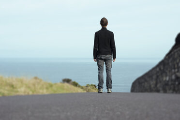 Portugal, Azoren, San Miguel, Mann steht auf der Straße und schaut auf das Meer - ONF000473