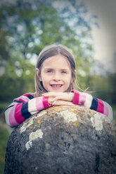 Portrait of little girl leaning on great stone - SARF000542