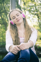 Portrait of female teenager with pink headphones daydreaming - SARF000555