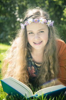 Portrait of female teenager lying on meadow with a book - SARF000558