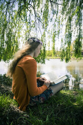 Weiblicher Teenager mit Buch unter Trauerweide sitzend - SARF000572