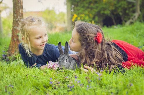 Zwei kleine Mädchen mit Kaninchen auf der Wiese liegend - MJF001107