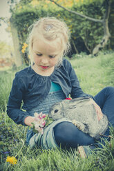 Little girl with rabbit sitting on meadow - MJF001108