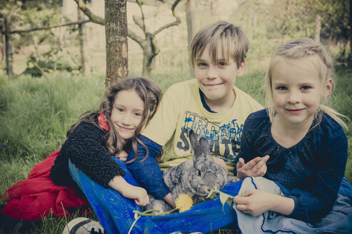 Drei Kinder mit Kaninchen auf einer Wiese sitzend - MJF001109