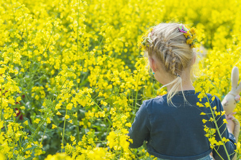 Kleines Mädchen schaut auf Rapsfeld, lizenzfreies Stockfoto