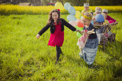 Drei Kinder unterwegs mit Holzwagen und Luftballons - MJF001114